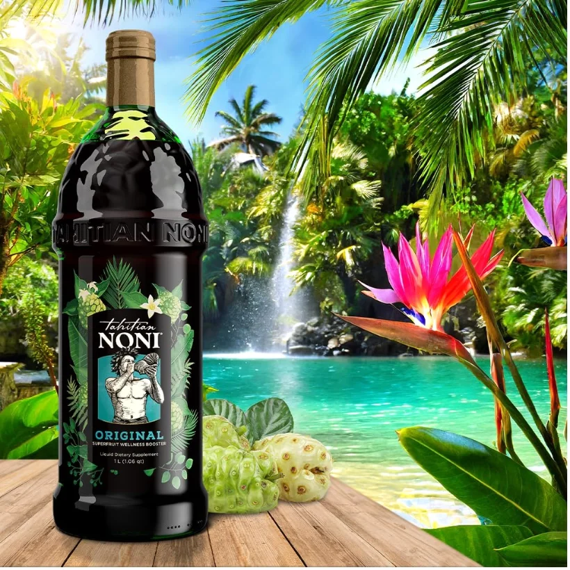 A bottle on a deck rail above the lagoon. The fruit in the frame is noni: green, knobbly, about the size of a small potato.